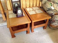 Pair of teak end tables with tile insets on carpeted floor near couch, showing their overall size and condition.