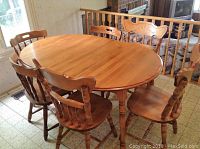 Maple oval dinette table with six maple dining chairs around it, showing the overall look and style.