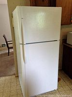 Front angled view of white Kenmore top-freezer refrigerator showing top freezer and bottom refrigerator doors with left-side handles.