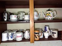 Full view of shelf with assorted mugs, two teapots, and soup bowls showing variety and arrangement