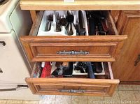 Two wooden drawers with assorted kitchen utensils including cutlery, utensils, and kitchen tools.