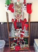 Full view of the cabinet with various Christmas decorations arranged on shelves including stockings, tinsel trees, and snowman figurines.