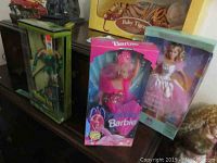 Photo shows all three Barbie dolls in their boxes arranged on a surface with visible packaging details for Mermaid and Peppermint Barbies.