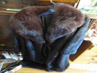 Front view of dark brown fur coat hung on Eaton's Fur Salon hanger