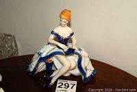 Front view of the Limoges porcelain figurine showing the woman holding a fan, seated in an elegant dress.