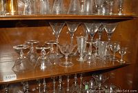 Shelf with assorted glassware including several clear glasses etched with cornflower floral design.