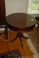 Round mahogany table showing top and four-leg pedestal base