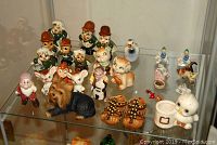Display of assorted ceramic figurines including dwarves, animals, a dog, shoes, and characters