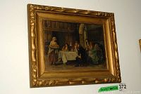 Photo showing the full framed oil painting hanging on a wall, featuring people around a dining table in a classical interior setting.