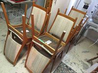 Six chairs stacked upside down showing wood frames and padded seats