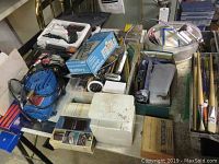 Photo showing assorted blue air compressor, boxes of drill bits, Weller soldering gun, Mastercraft multimeter, hand tools and small workshop items on a table.
