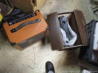 Overview showing both Roland amplifier and Kodak projector in case on concrete floor