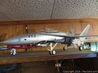 Silver fighter jet marked 456 with Swedish roundel and red practice bombs