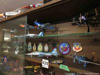Shelf display featuring multiple model airplanes including biplane and jet models alongside colorful military patches.
