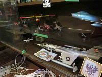 Multiple models in glass cabinet: CF-100 Canuck, North American F-86 on stand, futuristic silver jet, water bomber, other jets