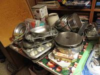 Overall assortment of baking pans, muffin tins, plastic grinder, and digital scale on table