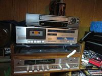 Full view of vintage stereo system with Dynatron SRX 25 receiver and turntable wood casing, TEAC cassette deck, and Emerson VCR stacked on top.