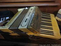 Pearl yellow Hohner accordion showing keyboard and bellows