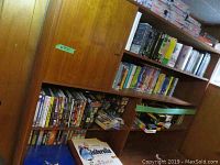 Photo of wooden shelves filled with multiple DVDs and VHS tapes, showing broad view of collection.