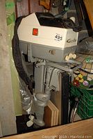 Side view of Gale outboard boat motor showing upper white cowling with logo and lower gray motor unit with propeller. Motor is stored upright and shows signs of wear.