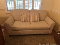 Front view of cream sofa sleeper with two matching pillows on seat.