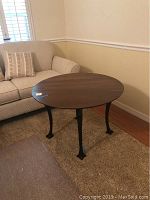 Full view of round wooden table near sofa showing legs and tabletop finish.