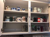 Full view of all shelves showing arrangement of 17 assorted coffee mugs in ceramic and glass with various colors and patterns.