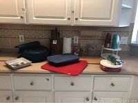 Overview of kitchen countertop holding various kitchen items including containers, knife block, pans, and plastic ware