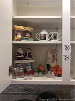 Cabinet shelf with assorted salt and pepper shakers including Christmas Santa pair, glass shakers, pumpkin and flower shaped shakers.