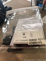 Photo of the wireless weather station and Bluetooth speaker device, packaged with instruction manuals and product documentation, showing part of the item under clear plastic packaging.