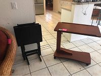 Dark brown portable TV room tray and dark brown TV dinner tables seen folded and upright adjacent to tray