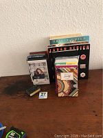 Photo of the entire lot showing books, photo album, cassette tape, and boxed item on a wooden surface.