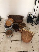 Photo showing all nine baskets arranged together on tile floor including large rectangular basket and picnic style basket with lid.