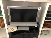 Toshiba 27 inch TV with silver frame and stand shown on a black table.