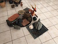 Wide shot of the entire collection of outdoor yard decor items on tiled floor, showing the duck, rocks, metal bird sculptures, dragon figure, lantern, and decorative tiles.