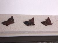 Three decorative metal fish sculptures mounted on wall, dark finish, approximately 10 inches high each.