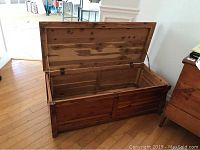 Cedar chest with open lid showing empty interior and wood grain inside.