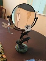 Full view of the round mirror with dolphin motif mounted on greenish stone base with brass frame and 7 inch circular mirror.