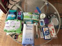 Overview of all packaged items including sanitary pads, incontinence underwear, soaps, flossers, razor, foot warmers, shower mirror and grip bar
