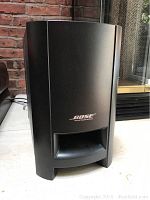 Front view of black Bose subwoofer speaker with port and logo centered on front panel.