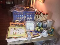 Full view of the Judaica items on the table including boxed electric menorah, traditional menorah, candles, cards, and small Passover items.