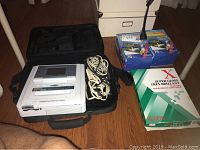 Sony DPP-EX7 digital photo printer in black carrying case with power cables and photo paper boxes and ream on floor