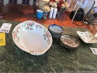 Seven pieces of ceramic decor and bowls arranged on a countertop with floral and blue designs.