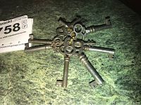 Six vintage-style metal skeleton keys arranged on a textured green surface.