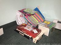 Overview of all items in the lot including board games (Scrabble and Battleship), gift bags, and stacks of greeting cards.