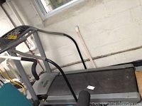 Side angle view showing treadmill belt and control panel area in a basement setting.