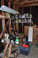 Workshop corner with shelves containing various bottles, oils, and tools arranged on tables and wooden shelves