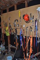 Full view of pegboard with hanging garden tools, straps, and hard hat.