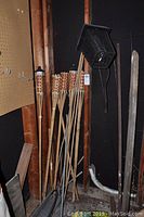 Six bamboo tiki torches leaning in corner, one black electric bug zapper hanging above.