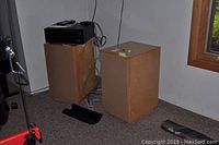 Two wooden speakers with an amplifier on top, showing setup and condition.